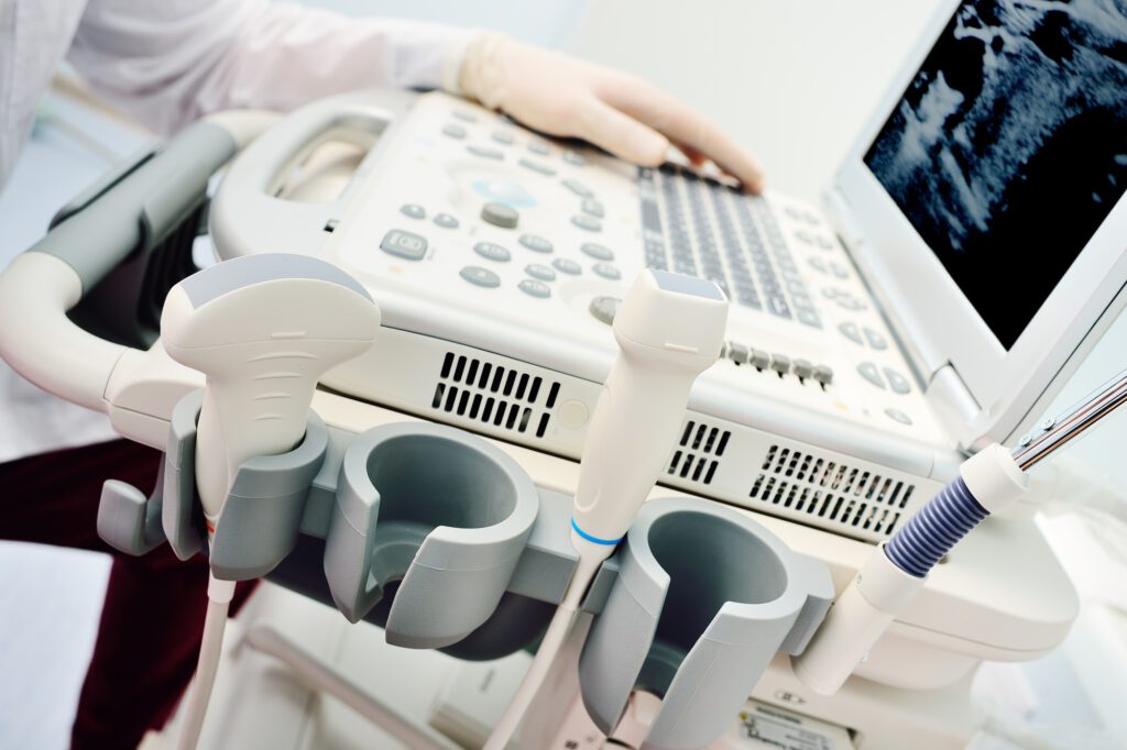 doctor's hands in medical gloves close-up against the background of a modern ultrasound machine
